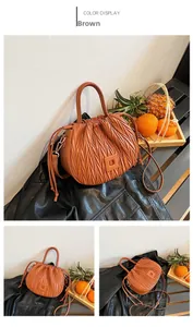 Detail of brown pleated drawstring bucket bag with leather texture and metal buckle