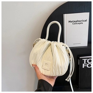 Close-up of white pleated mini bucket bag with glossy finish and drawstring details