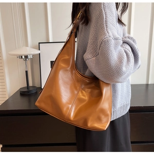 Gros plan d'un sac hobo marron caramel avec finition brillante et anneau en métal doré