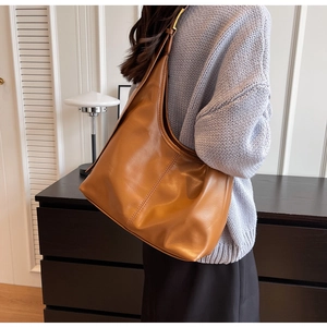 Vue latérale du grand sac hobo en cuir marron montrant les détails de couture et le drapé