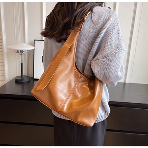 Grand sac hobo en cuir marron porté par un mannequin dans un décor minimaliste