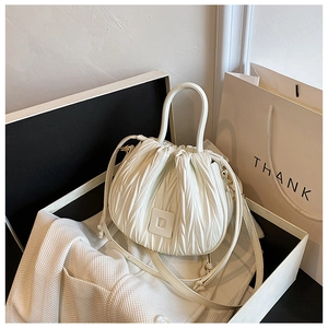 Detail of white pleated bucket bag with silver ring handle and adjustable strap