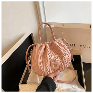 Detail of pink pleated bucket bag with drawstring closure and decorative buckle in a gift box