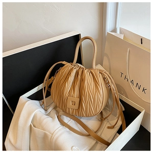 Detail of light brown pleated bucket bag in a gift box with adjustable shoulder strap