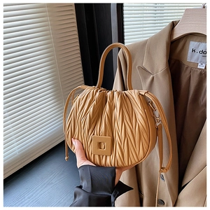 Detailed view of khaki ruched handbag featuring textured pleats and soft square buckle