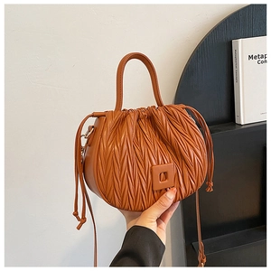 Detail shot of brown ruched bucket bag featuring a square buckle and side drawstring