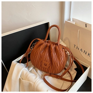 Detailed view of brown pleated cloud bag featuring soft synthetic leather and handles