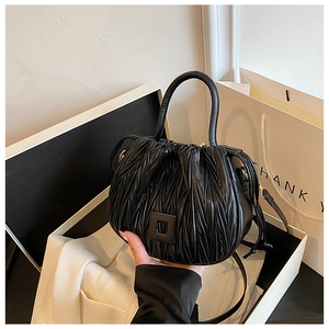 Detail of black pleated bucket bag with square buckle in a luxury gift box setting