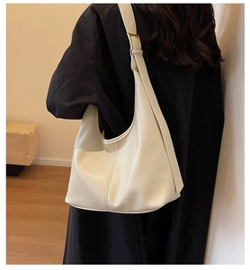Detail of cream white leather bucket bag with pebble texture and gold buckles