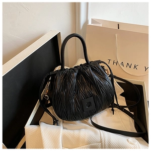 Close-up of black pleated PU bucket bag with drawstring and adjustable strap detail
