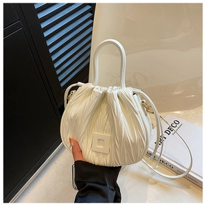 Detail of white pleated bucket bag featuring golden hardware and adjustable shoulder strap