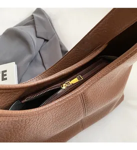 Detail of premium brown lychee pattern leather and gold metal zipper on a hobo bucket bag