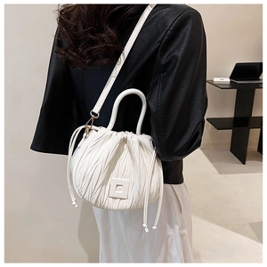 Detailed view of a white pleated drawstring bucket bag worn as a crossbody purse