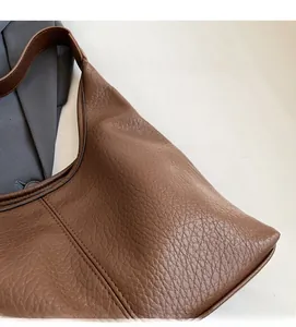 Detail of brown litchi pattern leather hobo bag with wide strap and soft stitching texture