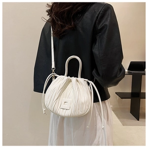 Detail of white pleated cloud bag showing drawstring closure and slim shoulder strap