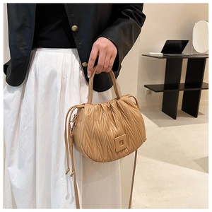 Close-up of khaki pleated bucket bag with cloud texture and square buckle detail