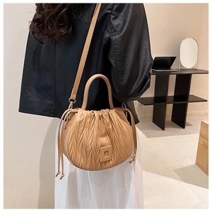 Detail of beige pleated dumpling bag showing leather texture and drawstring on a mannequin