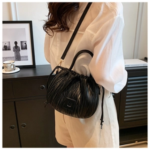 Detail of black pleated drawstring bucket bag styled on a female model shoulder