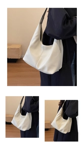 Macro detail of white hobo bag showing pebbled leather texture and wide shoulder strap