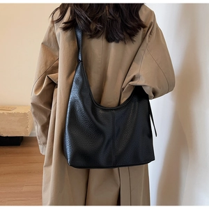 Close-up of black leather hobo bag with grainy texture and wide shoulder strap