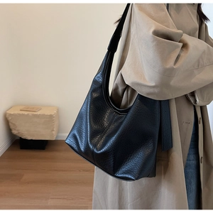 Detail shot of black hobo bag with pebble leather texture and stitching on wide shoulder strap
