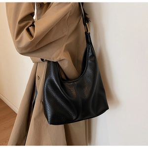Detailed view of black hobo bag with pebble leather texture and adjustable strap