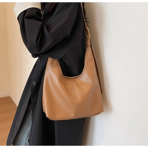 Detail of brown lychee grain leather texture and stitching on a large hobo bucket bag