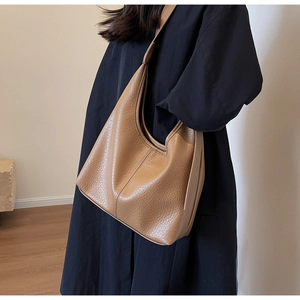 Close-up of brown litchi pattern leather hobo bag with wide shoulder strap on model