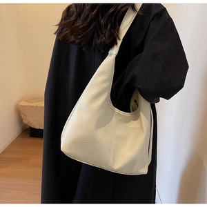 Detailed back view of a cream-colored pebbled leather hobo bag on a model shoulder