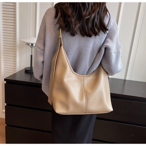 Macro shot of beige lychee-patterned leather texture and stitching on the bucket bag