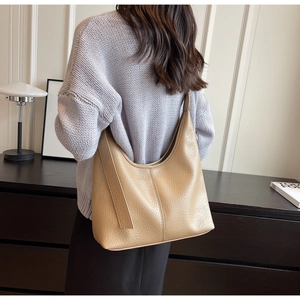 Detailed texture of apricot bucket bag with lychee pattern and fine stitching on the strap