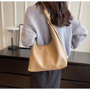 Detail view of khaki pebbled leather hobo bag with gold buckle and autumn styling