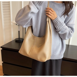 Detailed texture of beige lychee pattern leather shoulder bag shown on a model