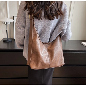 Detailed back view of a caramel brown leather bucket bag on a model showing large capacity