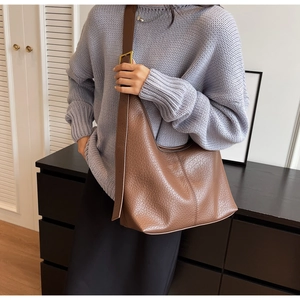 Detail of dark brown hobo bag with pebble leather texture and gold hardware on a strap