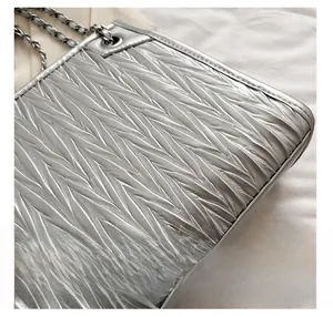 Detailed view of silver quilted matelassé texture and metallic chain strap on shoulder bag