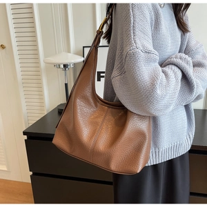 Detail showing brown lychee pattern leather shoulder bag with fine strap and golden buckle