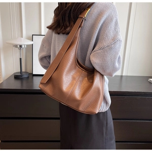 Detail of brown lychee texture leather hobo bag with adjustable strap and metallic buckle
