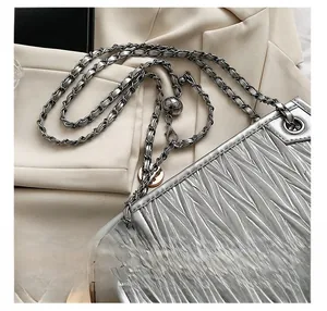 Detail of silver pleated chain bag with metal ball buckle and modern textured finish