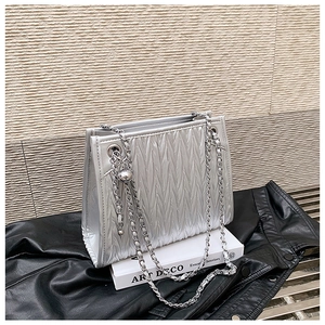 Close-up of silver textured shoulder bag with vertical pleats and metal chain strap