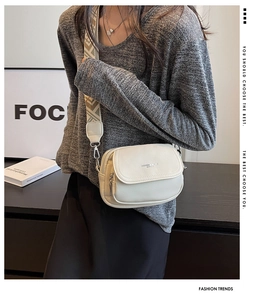 Détail du sac bandoulière en cuir grainé blanc cassé avec sangle tissée géométrique