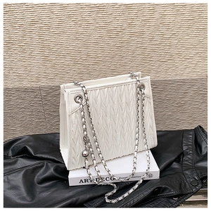 Detail of white matelassé leather handbag with silver chain and metal ball charm