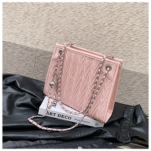 Detailed view of pink pleated leather bag with silver chain strap and metal ball decoration
