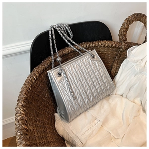 Detailed close-up of metallic silver quilted texture and silver chain on a tote bag