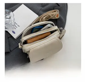 Détail du sac bandoulière en cuir grainé avec poches zippées et sangle en tissu jacquard