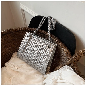 Close-up of silver matelassé shoulder bag with sleek metallic finish and chain strap