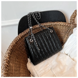 Detail of black quilted leather shoulder bag with silver chain and pleated texture