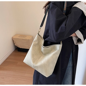 Detail of light green hobo bag featuring textured leather and a wide black strap