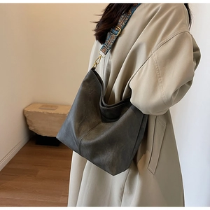Detail of dark grey hobo bag with colorful embroidered wide strap on beige trench coat