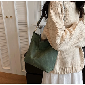 Detail of dark green suede tote bag featuring a retro colorful wide jacquard strap